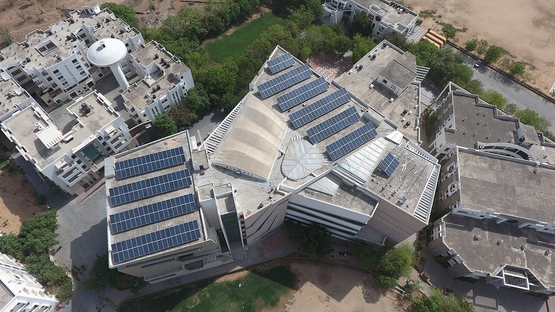 Aerial view of rooftop solar panels installed on institutional buildings in India, showing a typical rooftop solar installation